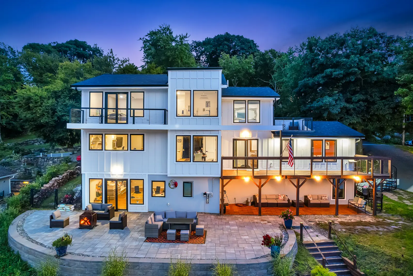 The house from the air above the lake, three storeys of white board and glass above a curved stone patio