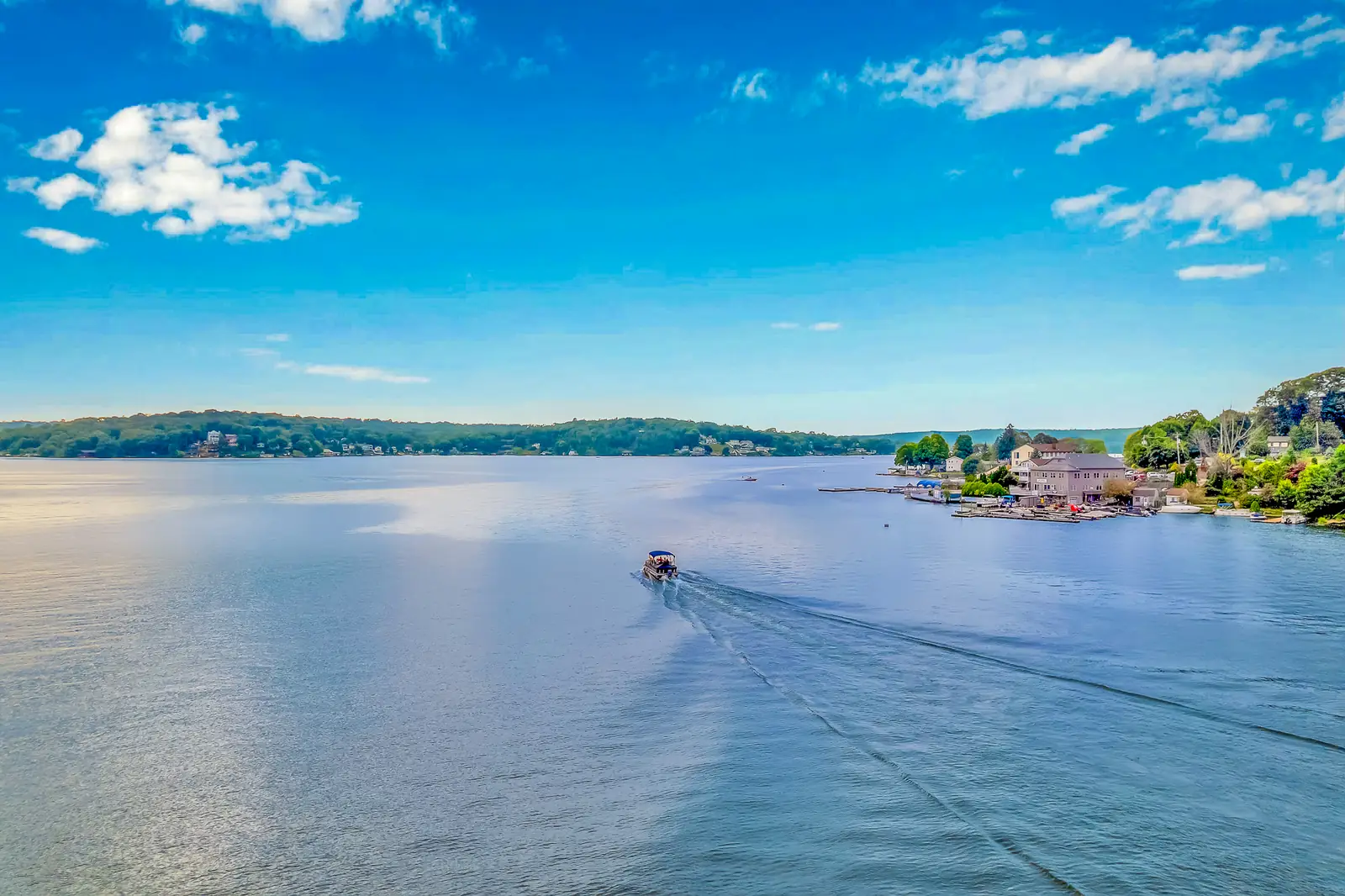 A single boat crossing the lake, its wake drawing a line across the water