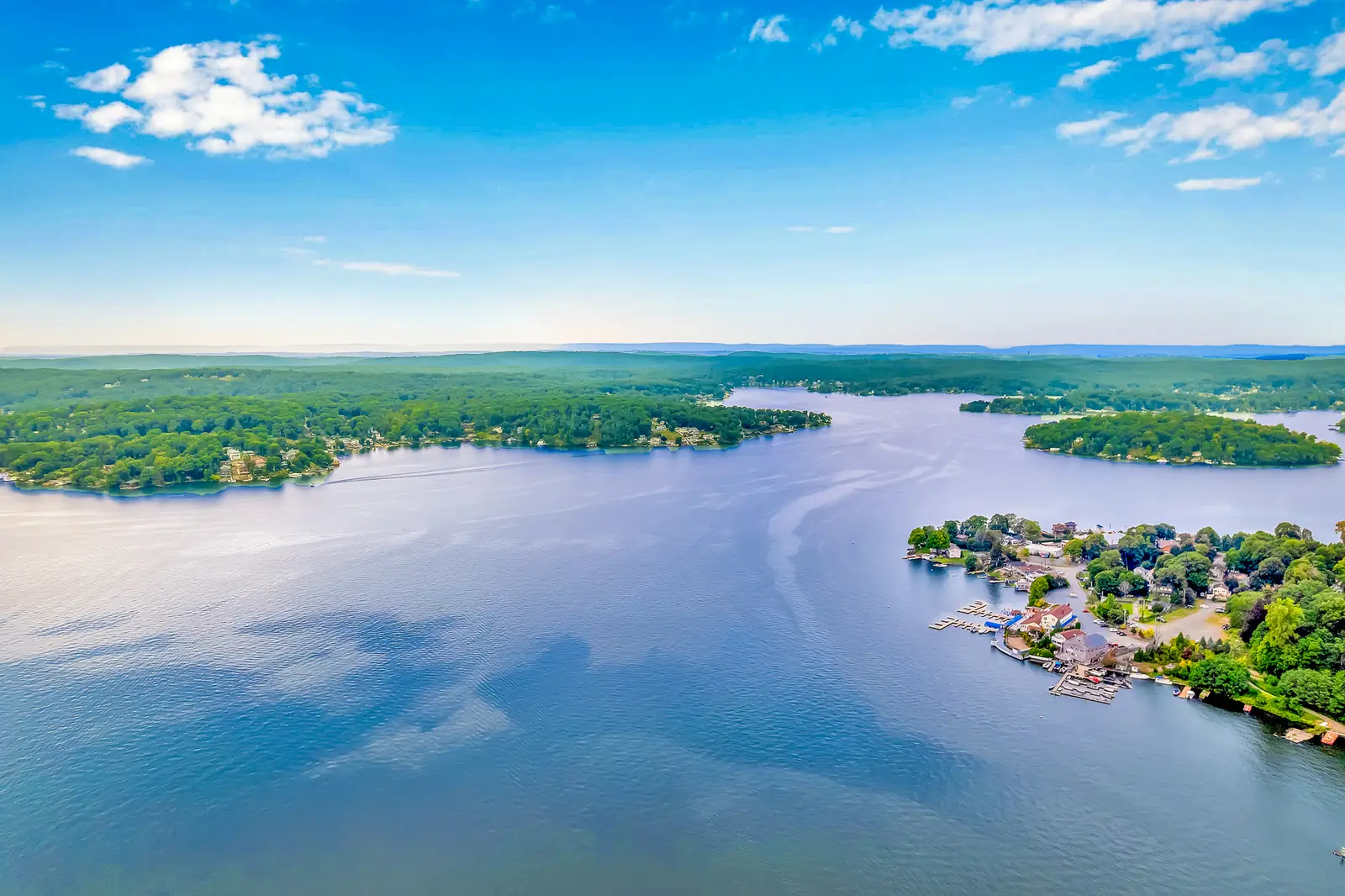 Lake Hopatcong from the air on a clear day, open water running between wooded points toward the hills