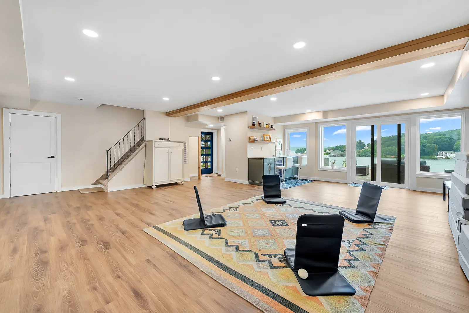 The retreat space: a long open room with meditation chairs on a patterned rug and the lake through a wall of windows