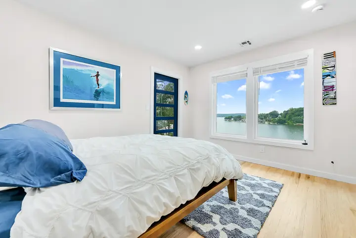 The Blue View: a queen bed, surf photographs on the walls, and the lake through a wide window