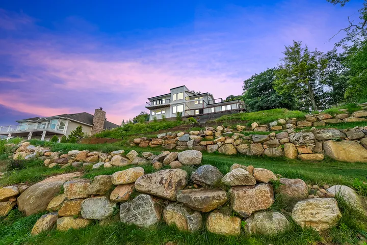 The house above its stone terracing at dusk, the sky going violet behind the trees