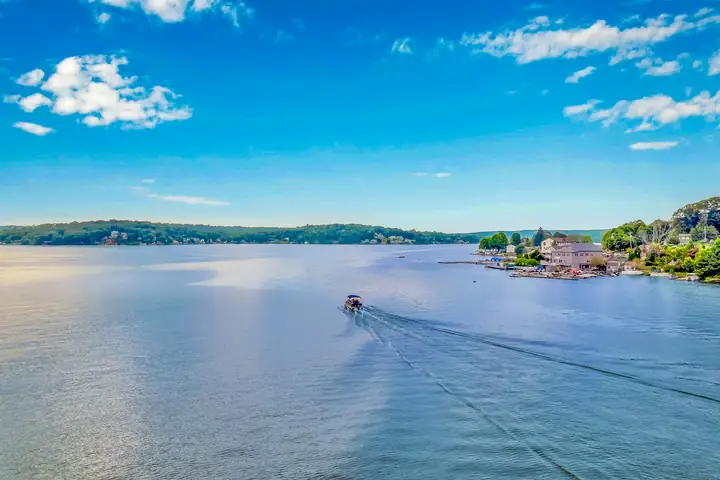 A single boat crossing the lake, its wake drawing a line across the water