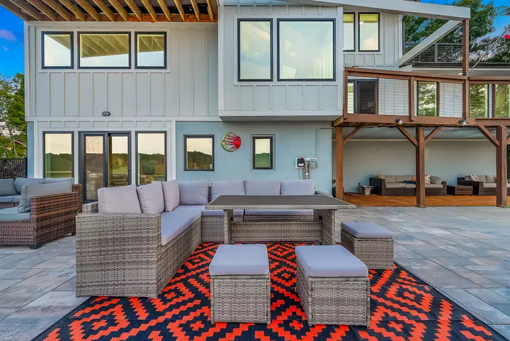 An outdoor dining table and sofa on a red patterned rug on the patio