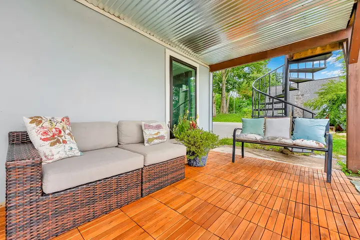 Sofas and a bench under the covered porch, a spiral stair beyond