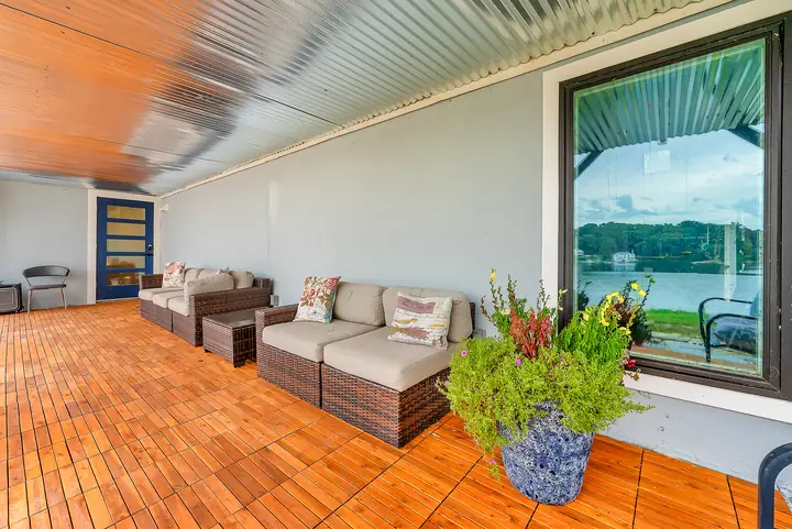 The covered porch on a teak floor, deep sofas facing the lake