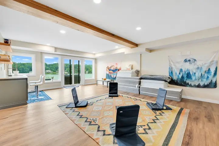 Meditation chairs in a circle, floor mats stacked by the wall, the lake beyond the windows