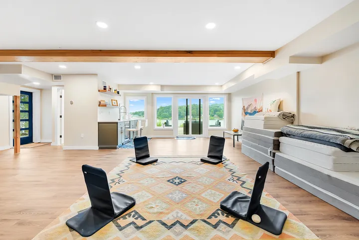 Meditation chairs set in a circle on the patterned rug, the doors to the lake open beyond them