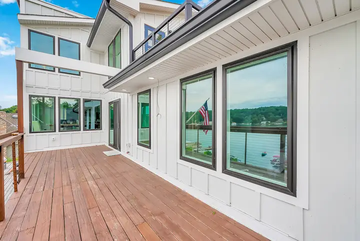 The upper deck along the side of the house, the lake beyond its rail